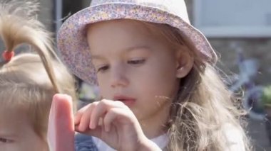 Close up portrait Girl enjoys delicious ice cream cone. Child eating watermelon popsicle. Kids Siblings snack sweets in Home Garden. Summer holiday Hot weather Sunny Day. Childhood, Food Candy Friends