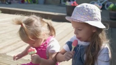 Two Sisters Children enjoys delicious ice cream cone. Child eating watermelon popsicle. Kids Siblings snack sweets in Home Garden. Summer holiday Hot weather Sunny Day. Childhood, Food Candy Friends.