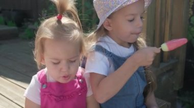 Two Sisters Children enjoys delicious ice cream cone. Child eating watermelon popsicle. Kids Siblings snack sweets in Home Garden. Summer holiday Hot weather Sunny Day. Childhood, Food Candy Friends.