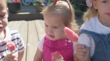 Three cute little Children enjoys delicious ice cream cone. Child eating watermelon popsicle. Kids Siblings snack sweets in Home Garden. Summer holiday Hot weather Sunny Day. Childhood, Food Candy.
