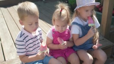 Three cute little Children enjoys delicious ice cream cone. Child eating watermelon popsicle. Kids Siblings snack sweets in Home Garden. Summer holiday Hot weather Sunny Day. Childhood, Food Candy.