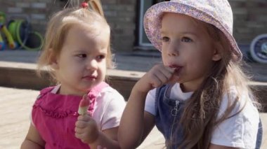 Two Sisters Children enjoys delicious ice cream cone. Child eating watermelon popsicle. Kids Siblings snack sweets in Home Garden. Summer holiday Hot weather Sunny Day. Childhood, Food Candy Friends