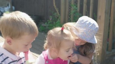 Three cute little Children enjoys delicious ice cream cone. Child eating watermelon popsicle. Kids Siblings snack sweets in Home Garden. Summer holiday Hot weather Sunny Day. Childhood, Food Candy.