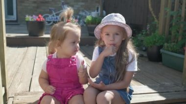 Two Sisters Children enjoys delicious ice cream cone. Child eating watermelon popsicle. Kids Siblings snack sweets in Home Garden. Summer holiday Hot weather Sunny Day. Childhood, Food Candy Friends.