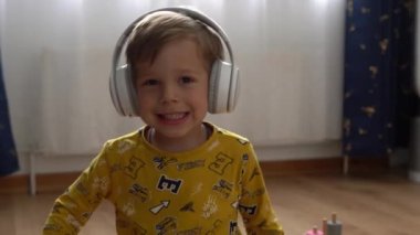 Kapalı mekanda müzik kulaklığı dinleyen yakışıklı çocuk. Çocuklar ve teknoloji. Müzik aşkı, çocuklar hayaller, hobiler. Yetenekli, mutlu, küçük çocuk kiralama. Çocukluk, müzik, hobi.