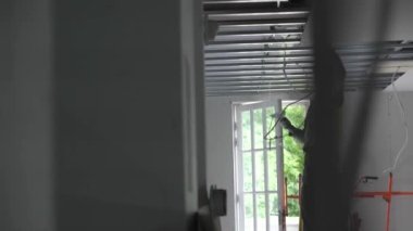 Hard male work on construction site. Two professional workers in special uniforms Contractors Safety Hats repairing ceiling wall inside building. Builders equipment at workplace. industrial premises.