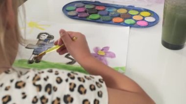 Talented Creative Child Girl Female Artist Draws with Her Hands on Paper, Using Fingers Paints Brush Creates Colorful, Kid Drawing on table at Home. Painter Creating Abstract Modern Art. Childhood.