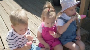 Three cute little Children enjoys delicious ice cream cone. Child eating watermelon popsicle. Kids Siblings snack sweets in Home Garden. Summer holiday Hot weather Sunny Day. Childhood, Food Candy.