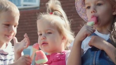 Three cute little Children enjoys delicious ice cream cone. Child eating watermelon popsicle. Kids Siblings snack sweets in Home Garden. Summer holiday Hot weather Sunny Day. Childhood, Food Candy.