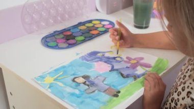 Talented Creative Child Girl Female Artist Draws with Her Hands on Paper, Using Fingers Paints Brush Creates Colorful, Kid Drawing on table at Home. Painter Creating Abstract Modern Art. Childhood.