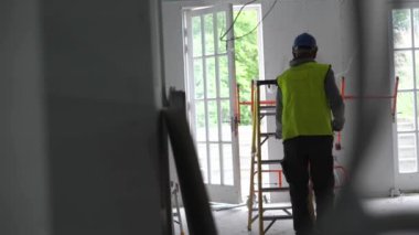 Hard male work on construction site. Two professional workers in special uniforms Contractors Safety Hats repairing ceiling wall inside building. Builders equipment at workplace. industrial premises.
