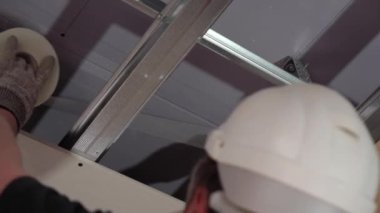 Hard male work on construction site. Two professional workers in special uniforms Contractors Safety Hats repairing ceiling wall inside building. Builders equipment at workplace. industrial premises.