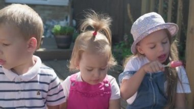 Three cute little Children enjoys delicious ice cream cone. Child eating watermelon popsicle. Kids Siblings snack sweets in Home Garden. Summer holiday Hot weather Sunny Day. Childhood, Food Candy.
