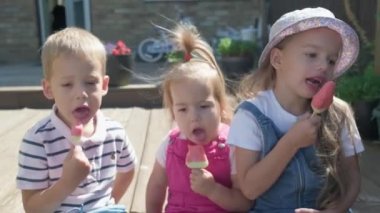 Three cute little Children enjoys delicious ice cream cone. Child eating watermelon popsicle. Kids Siblings snack sweets in Home Garden. Summer holiday Hot weather Sunny Day. Childhood, Food Candy.