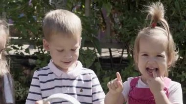 Portrait of Cute Little Three Children sitting on the beanch Garden. Cheerful Carefree Childhood. Preschool Siblings Friends Feeling Free Funky, Good Emotions Life. Home Dancing. Friendship Kids.