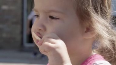 Close up portrait little Toddler girl enjoys delicious ice cream cone. Dirty Child Face eating popsicle. Kid snack sweets in Home Garden. Summer holiday Hot weather Sunny Day. Childhood, Food Candy.