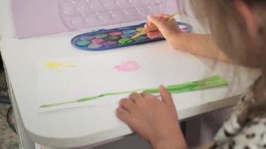 Talented Creative Child Girl Female Artist Draws with Her Hands on Paper, Using Fingers Paints Brush Creates Colorful, Kid Drawing on table at Home. Painter Creating Abstract Modern Art. Childhood.