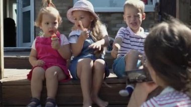 Woman Films Children On Camera. Three Friends Enjoys Delicious Ice Cream Cone. Child Eat Watermelon Popsicle. Siblings Snack Sweets In Home Garden. Summer Holiday Hot Sunny Day. Childhood, Home video