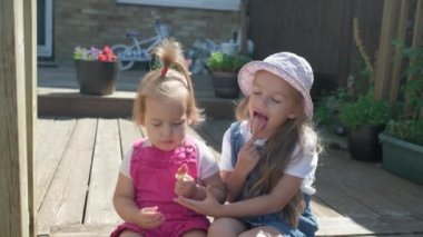 Two Sisters Children enjoys delicious ice cream cone. Child eating watermelon popsicle. Kids Siblings snack sweets in Home Garden. Summer holiday Hot weather Sunny Day. Childhood, Food Candy Friends.