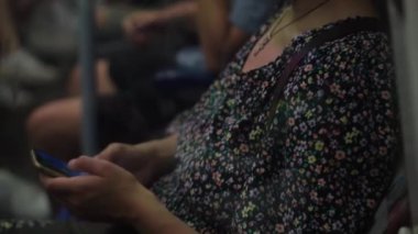Close shot of young attractive Ukraine female in glasses sitting on moving city metro train. Woman calling typing text message on mobile phone. Pretty Lady waving hands say goodbye. Traveling alone.