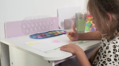 Talented Creative Child Girl Female Artist Draws with Her Hands on Paper, Using Fingers Paints Brush Creates Colorful, Kid Drawing on table at Home. Painter Creating Abstract Modern Art. Childhood.
