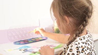 Talented Creative Child Girl Female Artist Draws with Her Hands on Paper, Using Fingers Paints Brush Creates Colorful, Kid Drawing on table at Home. Painter Creating Abstract Modern Art. Childhood.