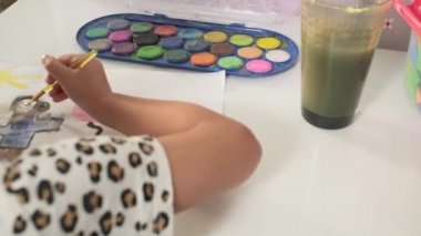 Talented Creative Child Girl Female Artist Draws with Her Hands on Paper, Using Fingers Paints Brush Creates Colorful, Kid Drawing on table at Home. Painter Creating Abstract Modern Art. Childhood.