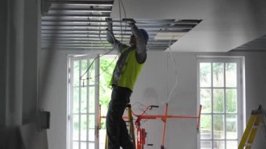 Hard male work on construction site. Two professional workers in special uniforms Contractors Safety Hats repairing ceiling wall inside building. Builders equipment at workplace. industrial premises.