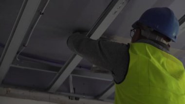 Hard male work on construction site. professional worker in special uniforms Contractors Safety Hats repairing ceiling wall inside building. Builders equipment at workplace. industrial premises.