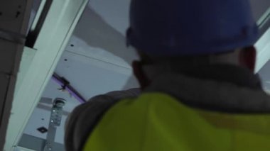 Hard male work on construction site. professional worker in special uniforms Contractors Safety Hats repairing ceiling wall inside building. Builders equipment at workplace. industrial premises.
