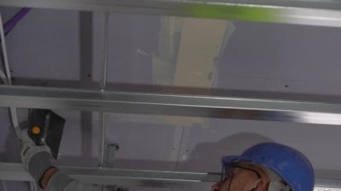 Hard male work on construction site. professional worker in special uniforms Contractors Safety Hats repairing ceiling wall inside building. Builders equipment at workplace. industrial premises.