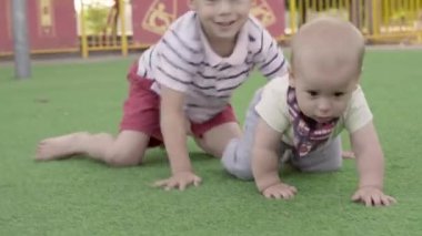 Mutlu aile piknik yapıyor. Küçük bebek yeşil çimlerde sürünüyor. Park yazında. Green Park 'ta oynayan kardeşler. Oyun salonunda aile eğlencesi ve neşe. Aktif oğul tarlada sürünüyor..