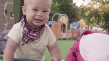 Bebek dışarıda duruyor. Küçük bebek yeşil çimlerde sürünüyor. Park yazında. Green Park 'ta oynayan kardeşler. Oyun salonunda aile eğlencesi ve neşe. Aktif oğul tarlada sürünüyor..