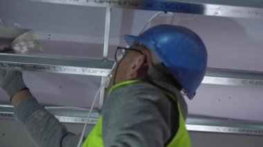 Hard male work on construction site. professional worker in special uniforms Contractors Safety Hats repairing ceiling wall inside building. Builders equipment at workplace. industrial premises.