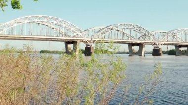 Gün batımında Dnipro nehrinde yüzen balıkçı teknesinin manzarası. Şehirdeki göl üzerindeki sanayi köprüsünün manzarası. Kamyon ve araba güneşli yaz günlerinde göletin üzerinden geçer. Su taşır, seyahat eder..