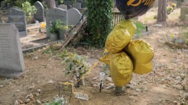 Eski Terk Edilmiş Mezarlık, Yaz Günü. Mezarlıkta Anıt Çiçekleri ve Mezar taşında Doğum günün kutlu olsun yazan balonlarla. Ölümden sonraki yaşam. Cenaze Servisi. Dini Gelenek.