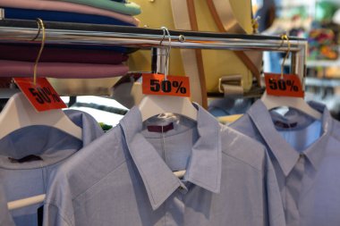 İndirim etiketleri% 50 indirimli. Günlük ya da ev kıyafetleri satan mağazalardaki askılarda. Moda konsepti, indirim sezonu, kara Cuma, çevrimdışı alışveriş, numaralar, tatil satışları, pijamalar. Yan görünüm.