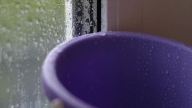 Çatı ya da balkon şiddetli yağmur nedeniyle sızdırıyor, damlalar kovaya damlıyor. Yakın plan. Acil durum konut, arıza, tamirat kavramı. Daha sonra dengelenmiş elle ateş etme..