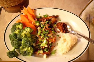 Barbekü tavuk tarifi, dilimlenmiş yeşil biber ve bebek soğanları taze organik sebze brokoli, havuç ve yapışkan pirinçle yenir. Sağlıklı yiyecekler ve Tayland yemeği tarzıyla evde kolay aşçı..