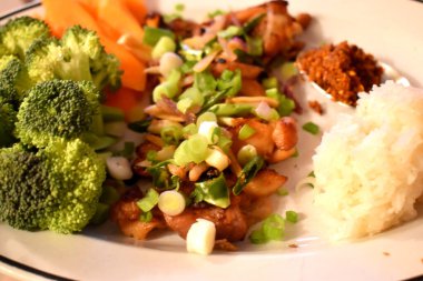 Biber dilimli kızarmış tavuk ve taze organik sebzeli brokoli, havuç ve yapışkan pirinçle yenen baharatlı biber ezmeli soğan. Sağlıklı yiyecekler ve Tayland yemeği tarzıyla evde kolay aşçı..