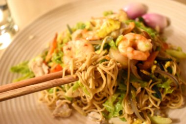 Karides ve organik sebzelerle karıştırılmış yumurta eriştesi üzerine yemek çubukları, sağlıklı Tayland baharatlı yemek tarzıyla evde kolay pişirme..