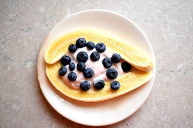 Masada dilimlenmiş muz, yaban mersini ve yoğurt karışımı. Kahvaltı için lezzetli ve sağlıklı yemek..