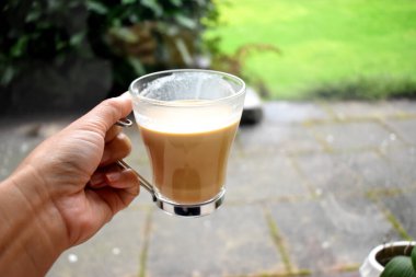 Arka planda cam bir fincan sıcak kahveyi tutan insan eli. Sabahları organik taze kavrulmuş kahve..