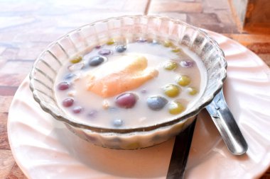 Thai tatlı Bua Loy Khai Hwan (Şamandıra Tatlı Yumurta, Hindistan cevizi sütlü tatlı küçük hamur tatlısı.) Masadaki beyaz tabakta cam bir kasede..