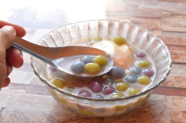 Bir kaşık dolusu Tayland tatlısı Bua Loy Khai Hwan (Şamandıra Tatlı Yumurta, Hindistan cevizi sütlü tatlı küçük hamur tatlısı). Masanın üzerinde..