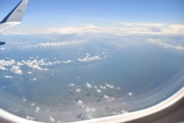 See-through aircraft a window at high altitude and beautiful high-altitude clouds floating over the sea on a sunny day.