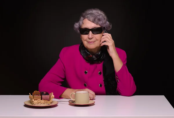 Бабушка в темно-розовой куртке говорит по мобильному телефону — стоковое фото
