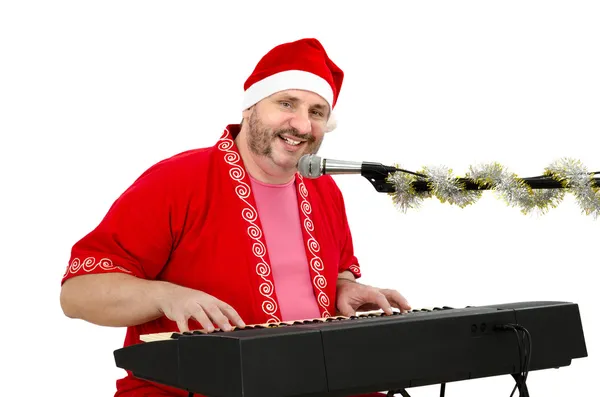 Muž v obleku santa Clause se baví s elektrické piano — Stock fotografie