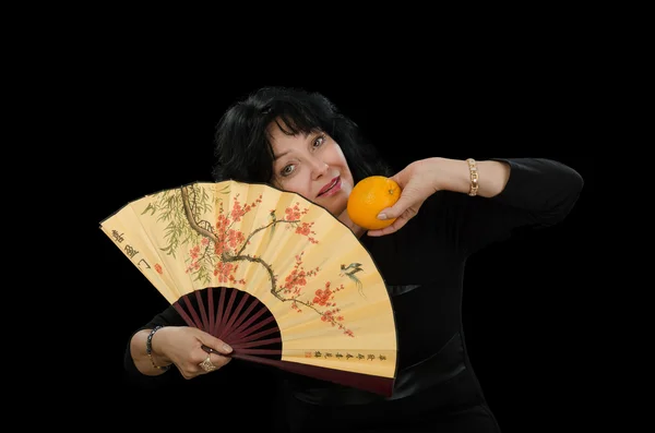 Зрелая актриса с веером и апельсином — стоковое фото