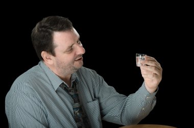Mature guy looks at shot of vodka clipart